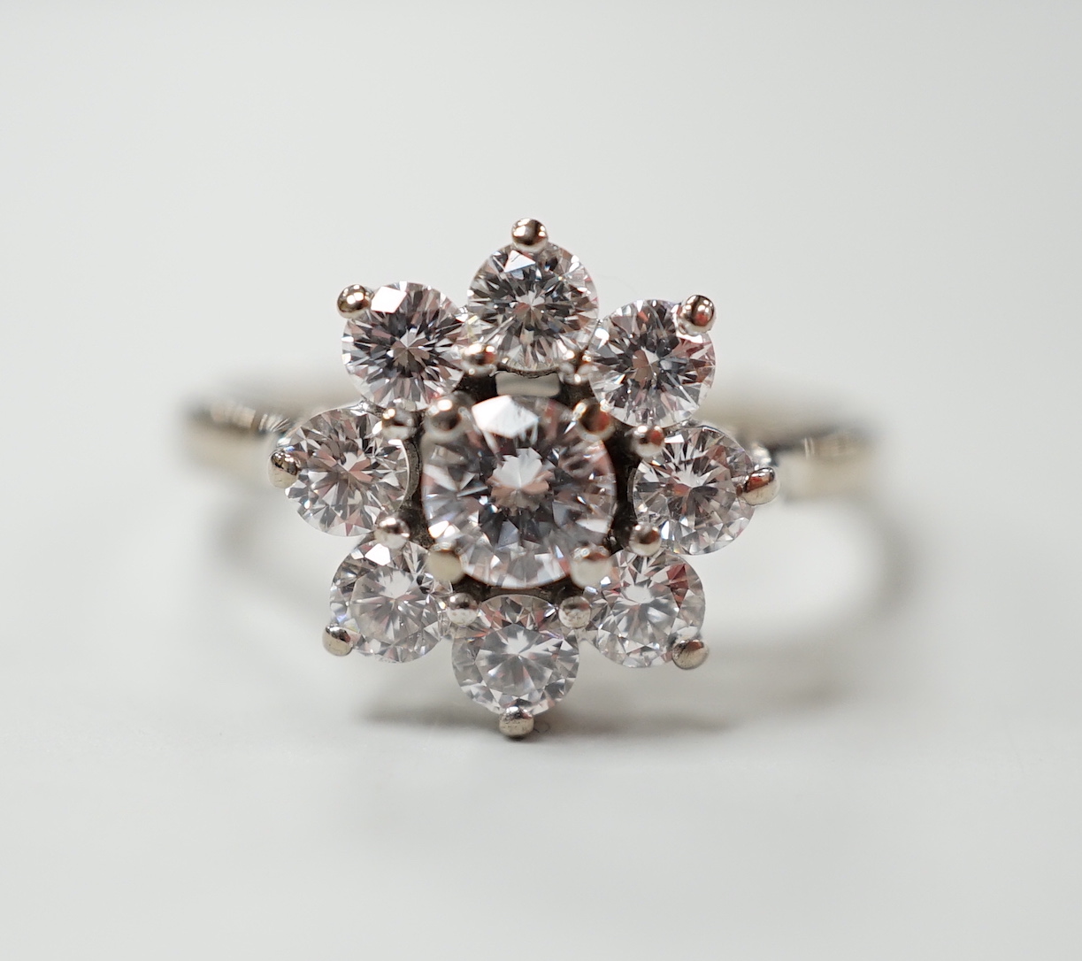 An 18ct, plat. and nine stone diamond set flower head cluster ring, the central stone weighing approximately 0.25ct, size O, gross weight 4 grams.